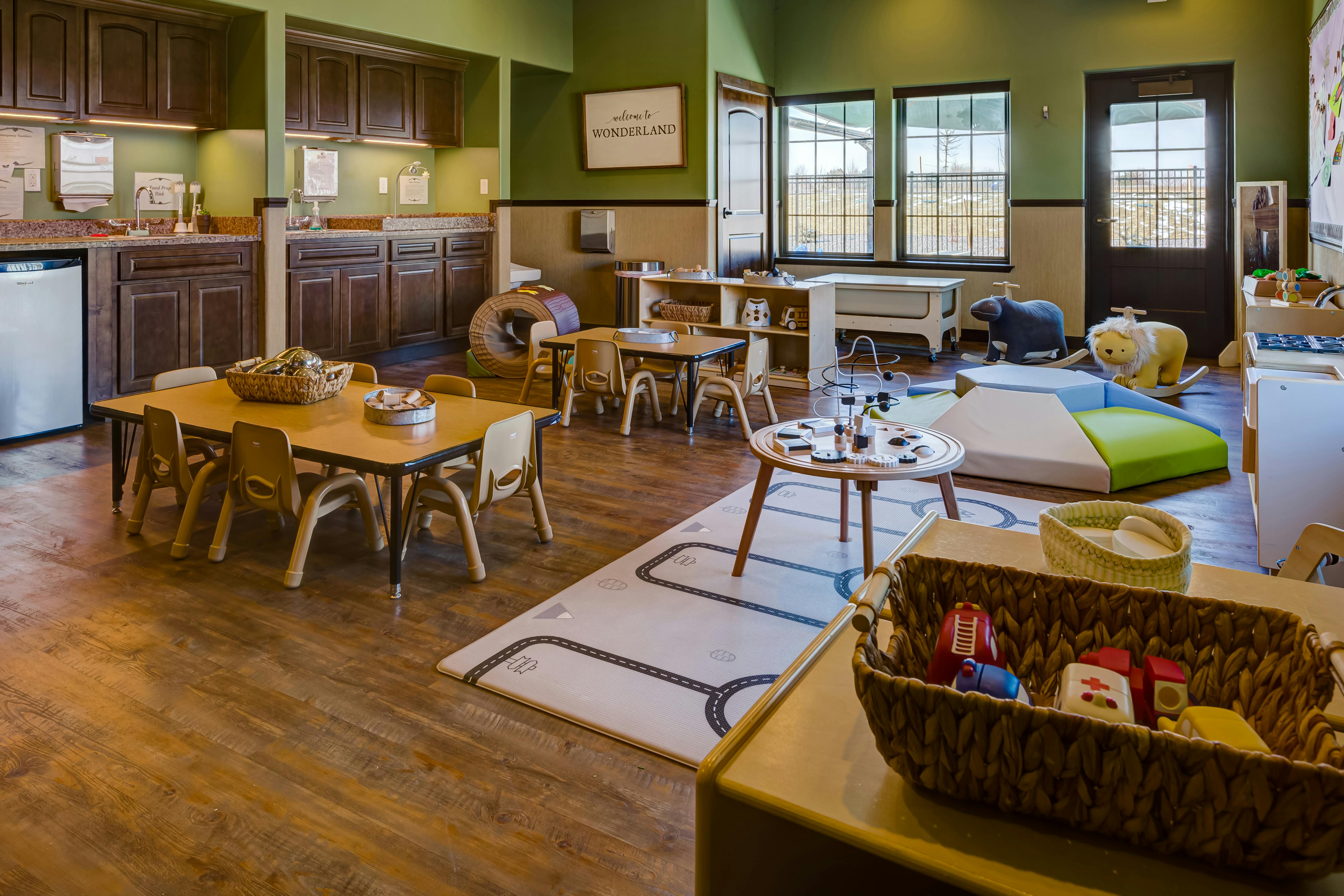 Playroom with small tables and chairs, kitchen area, and play mats