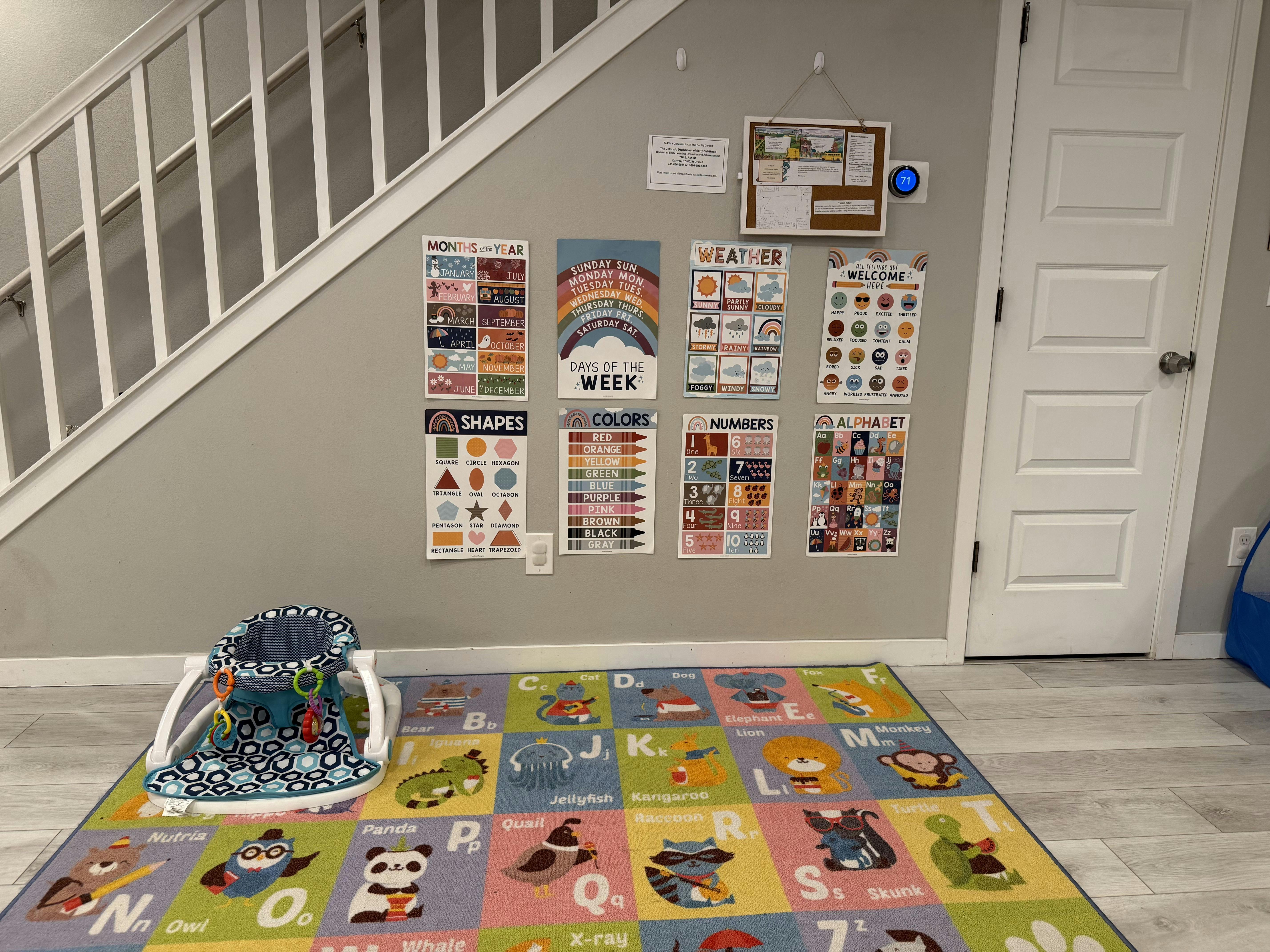 Educational posters on a wall above a child activity rug and a floor seat