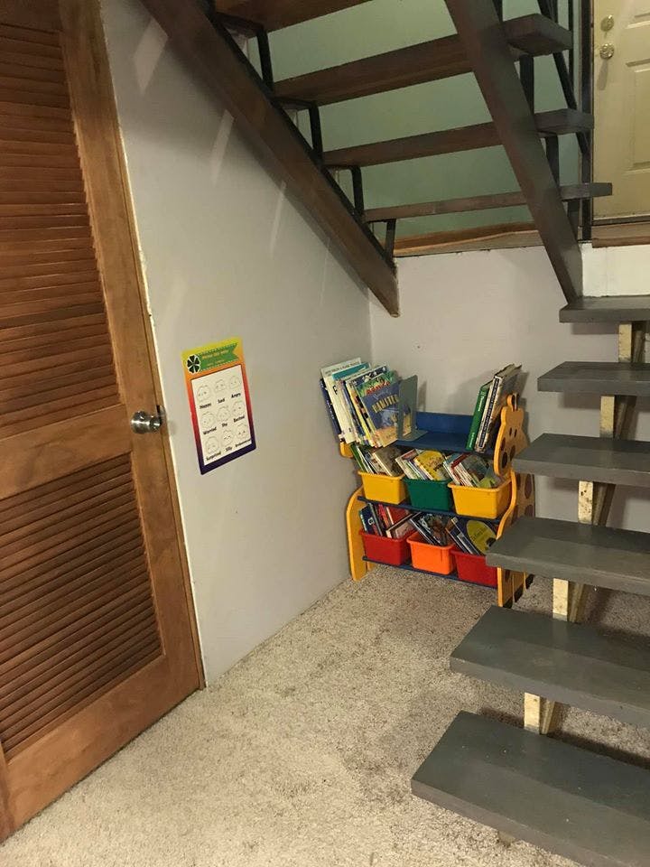 Bookshelf with colorful bins under a wooden staircase