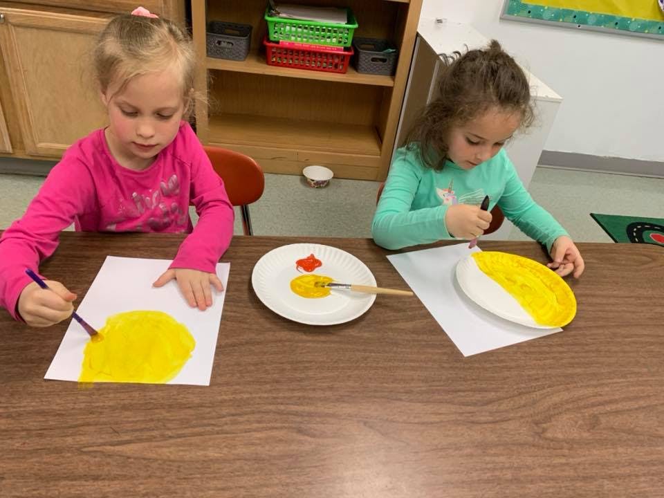 Two children painting at a table