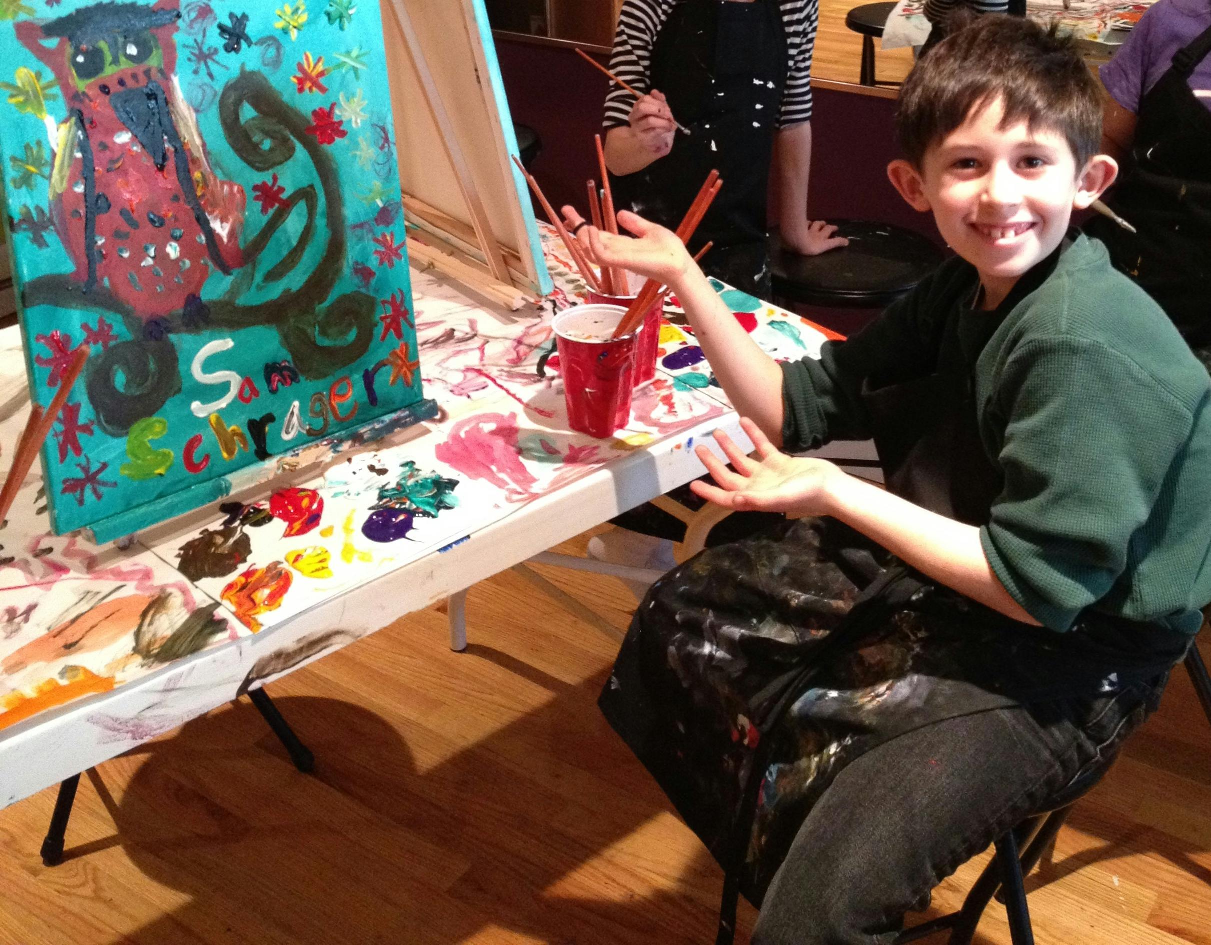 Child painting at an easel with a colorful painting