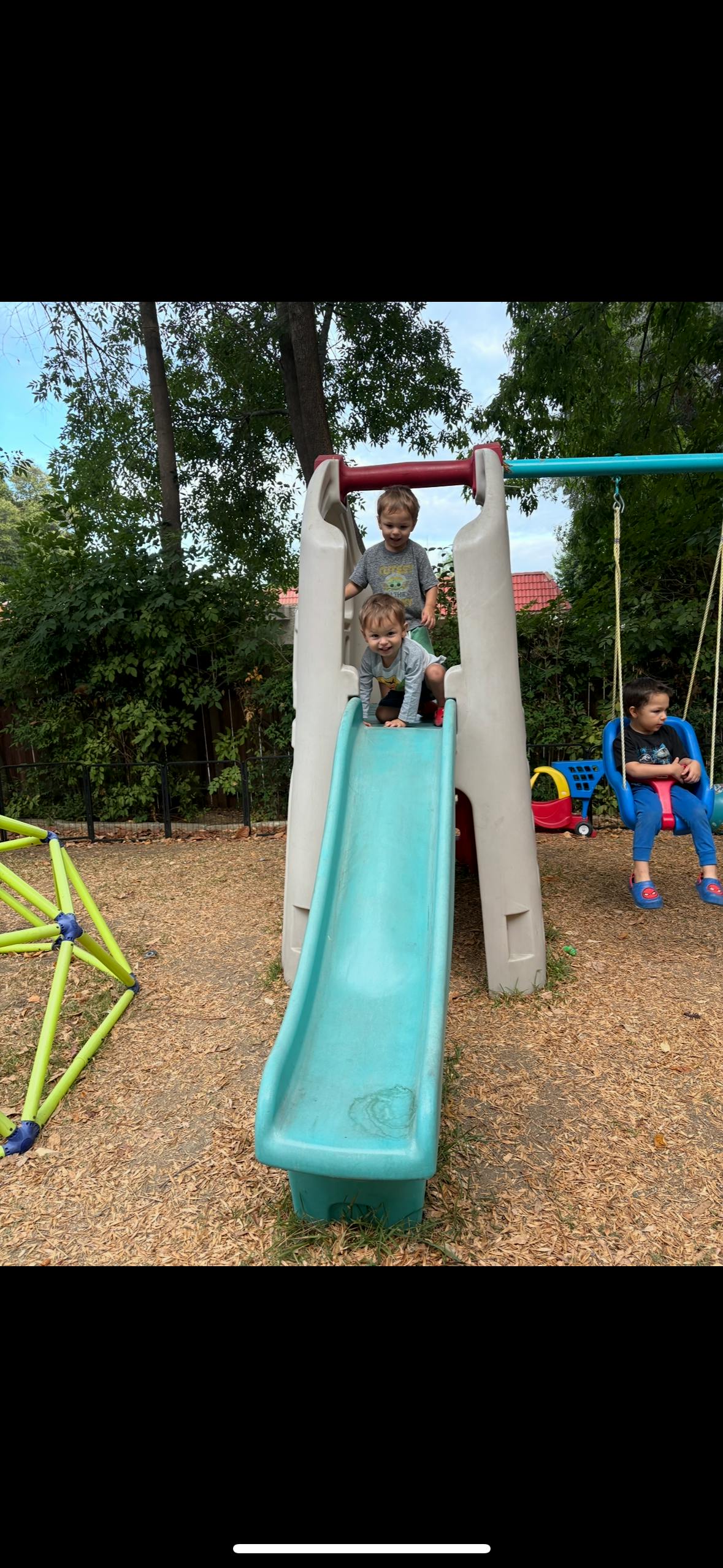 Children playing on a playground slide and swing set