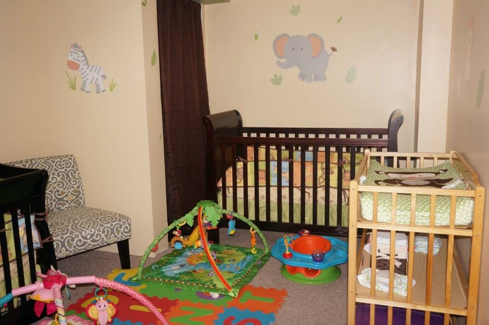 Nursery room with two cribs, a changing table, and play mats