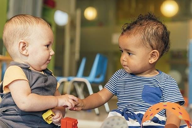 Two children holding hands in a classroom