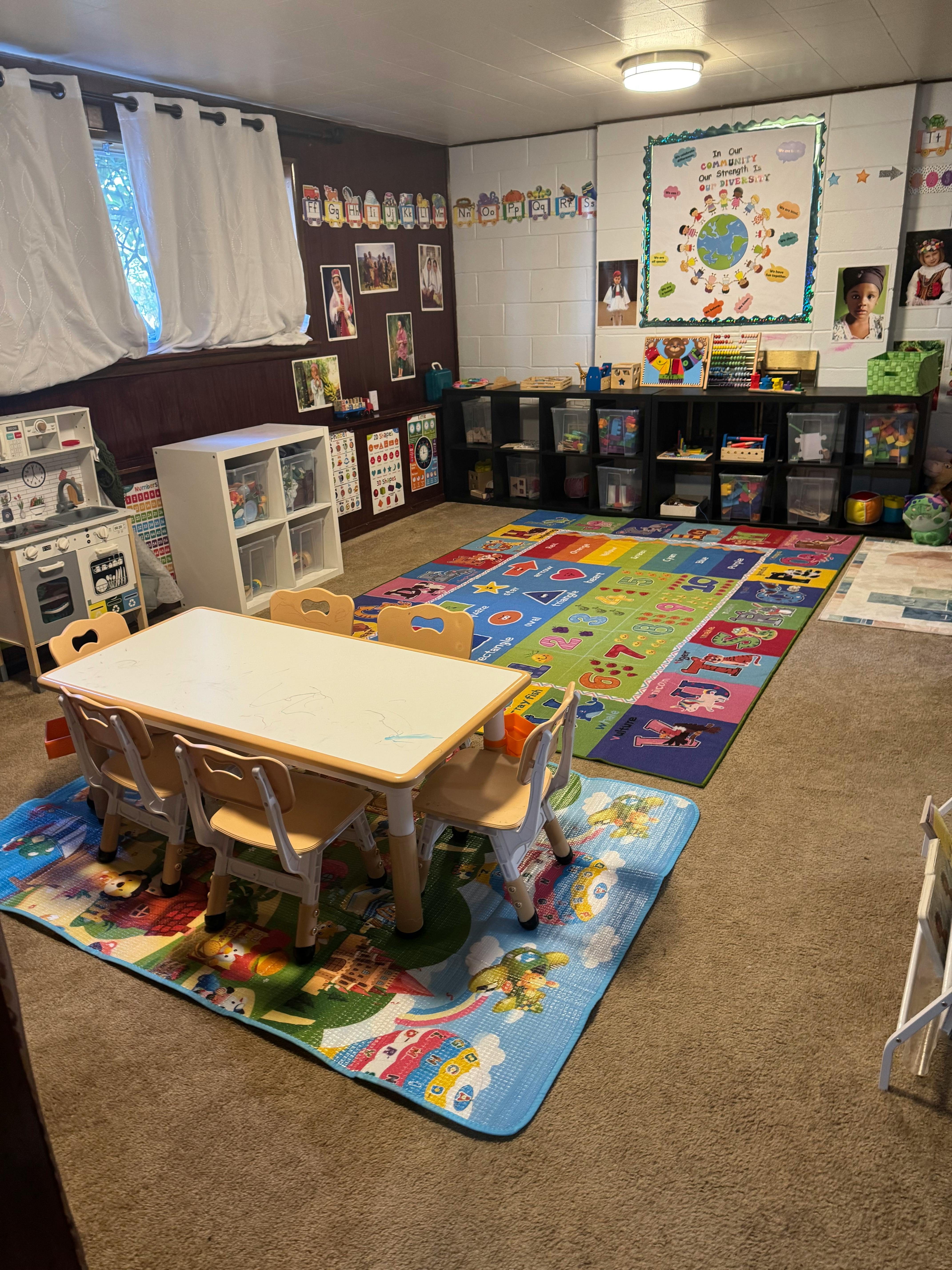 Classroom with small table and chairs, colorful rugs, and storage shelves