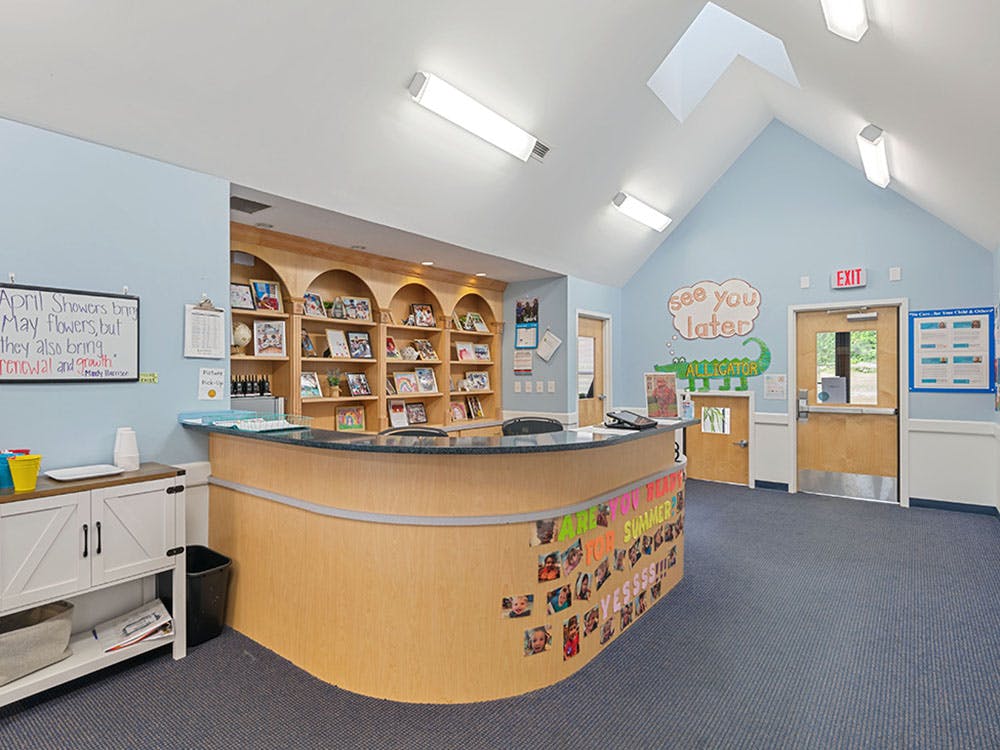 Reception desk with arched shelves filled with framed photos and decorative wall art