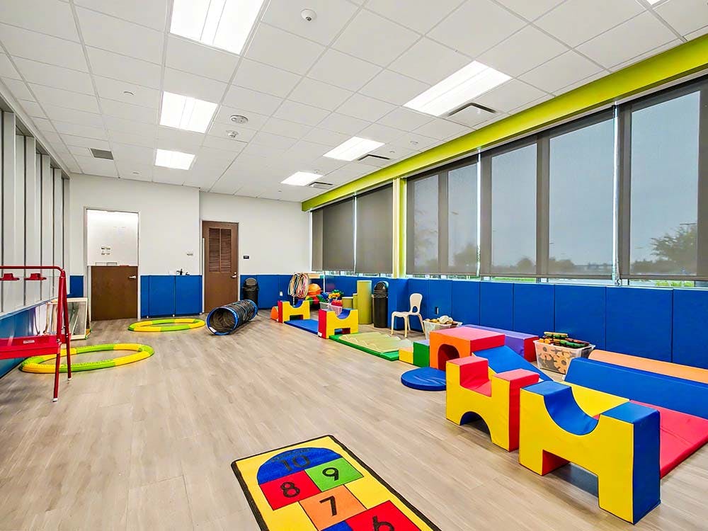 Indoor play area with colorful soft play equipment, tunnels, and floor games