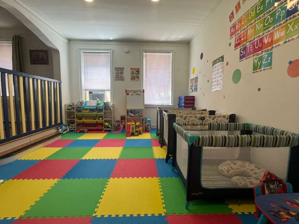 Childcare room with colorful floor mats, playpens, and alphabet wall decorations