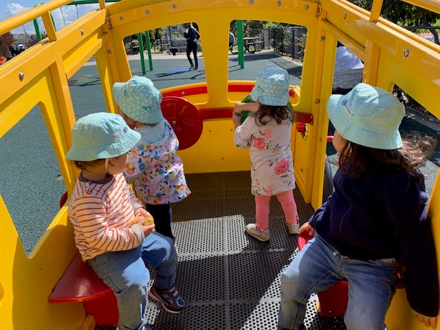 Four children playing inside a yellow playground structure
