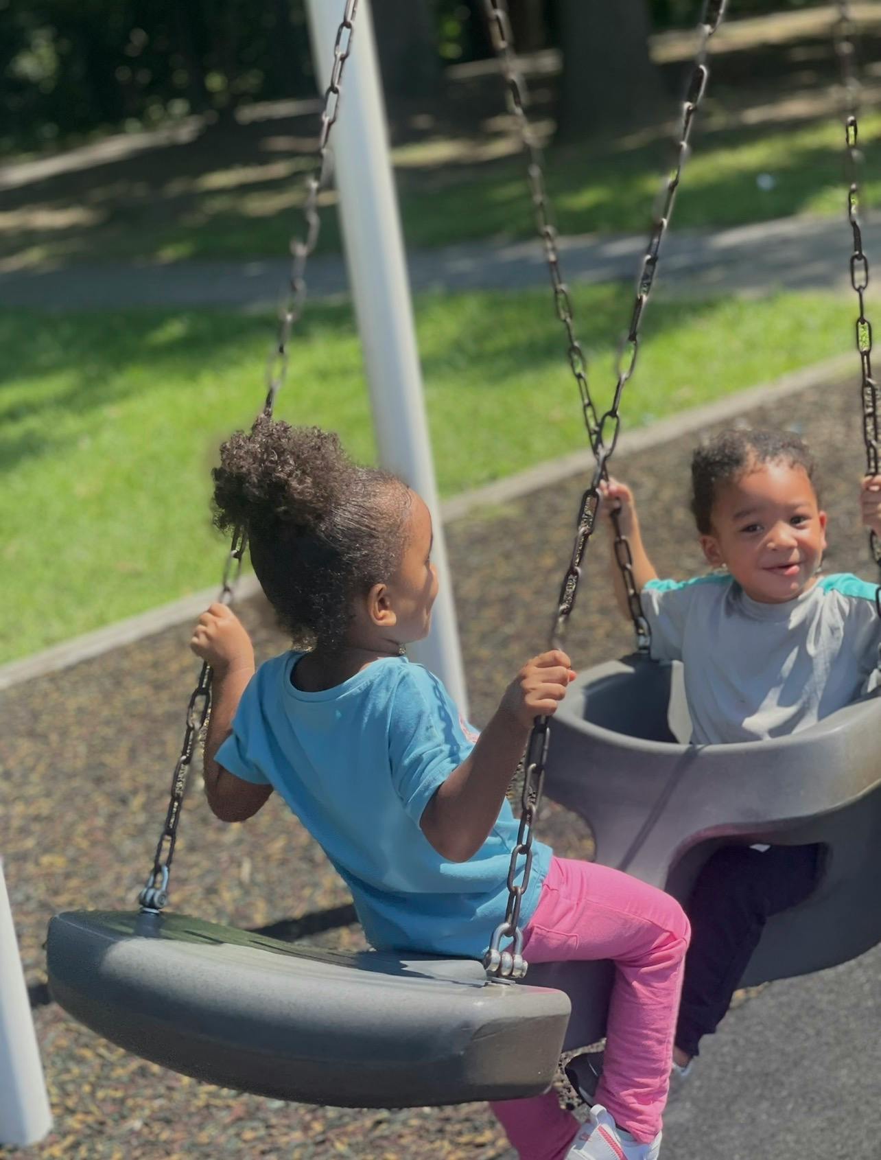 Two children sitting on playground swings