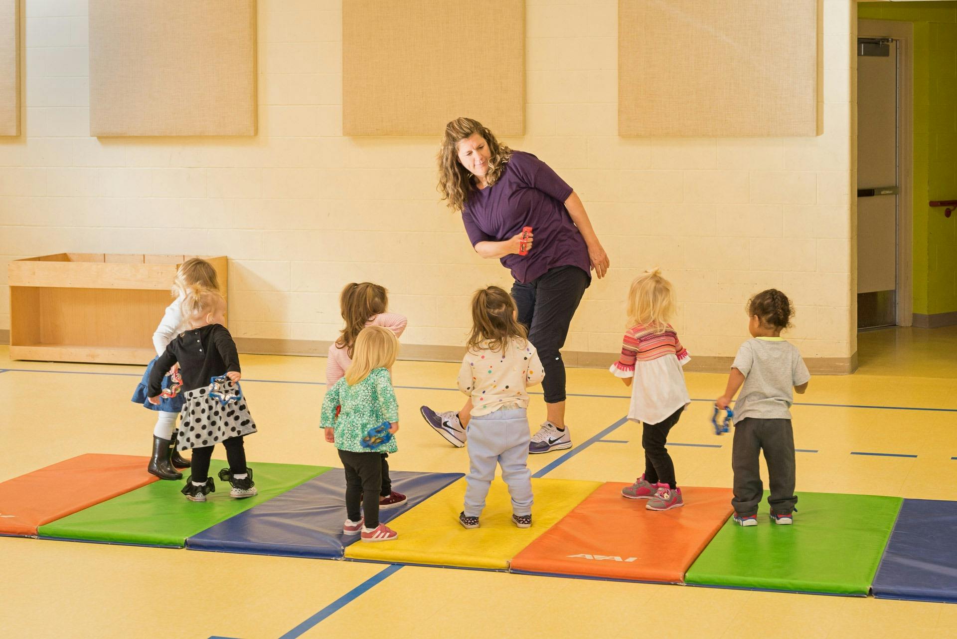 Adult and children on colorful mats in a room