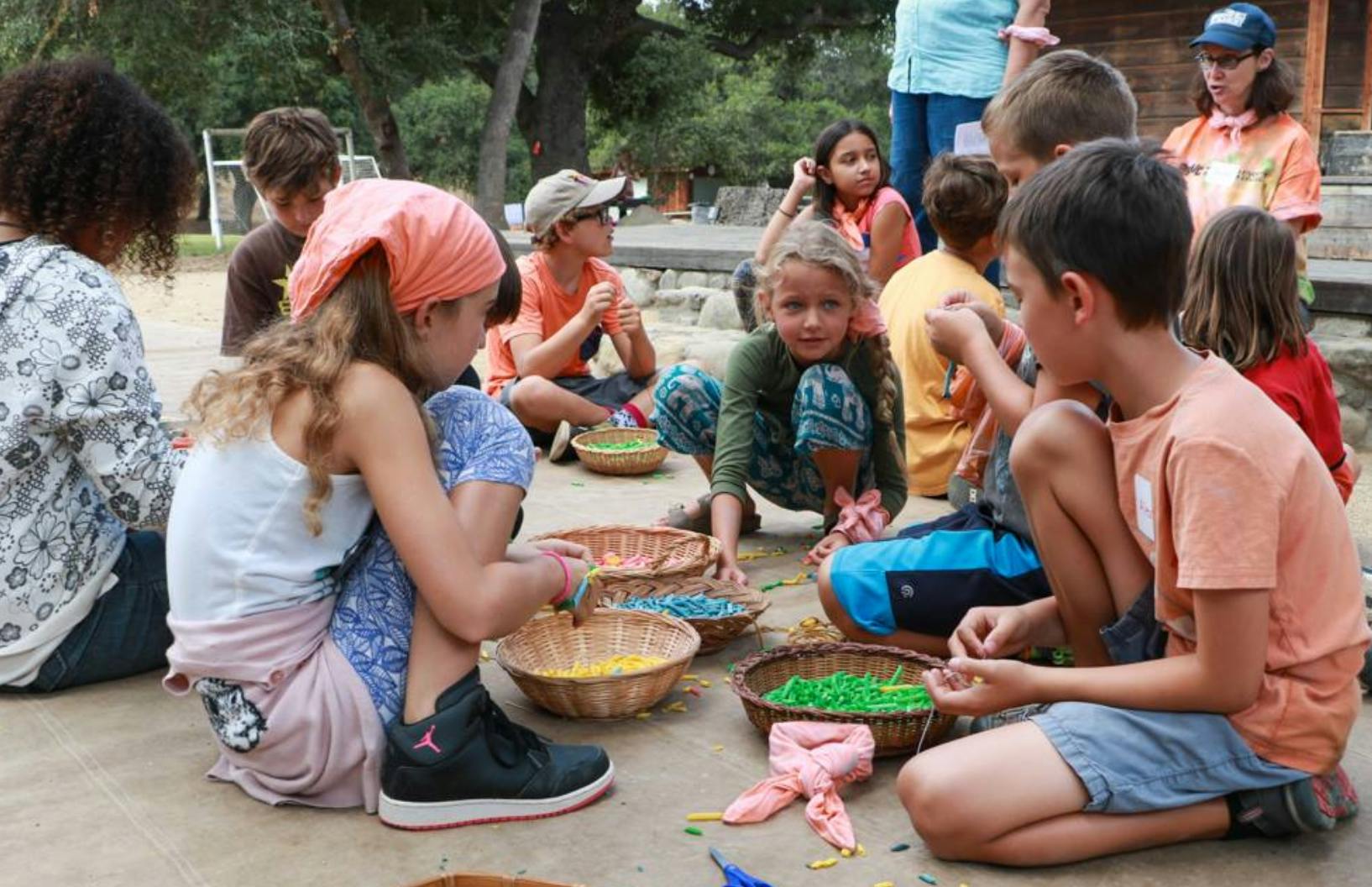 Children sitting on the ground with baskets of colorful items
