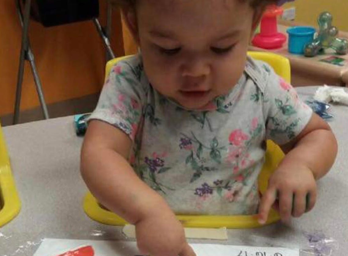 Child in a high chair looking down at a table