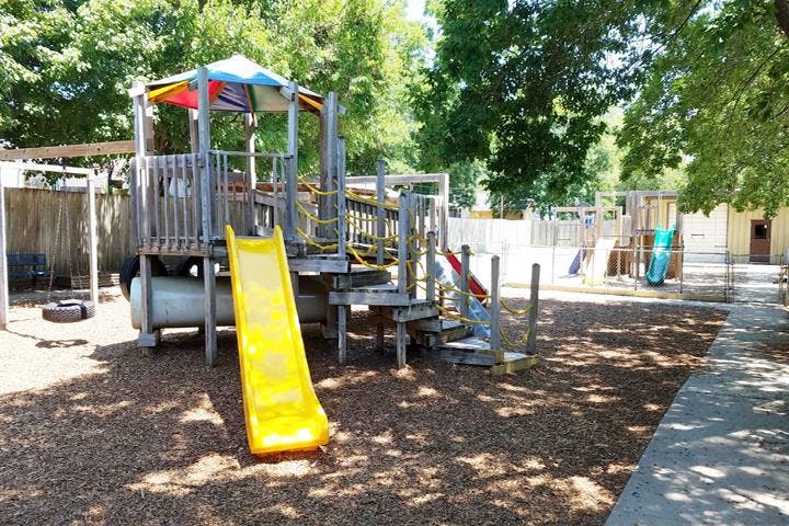 Playground with a yellow slide and wooden structure