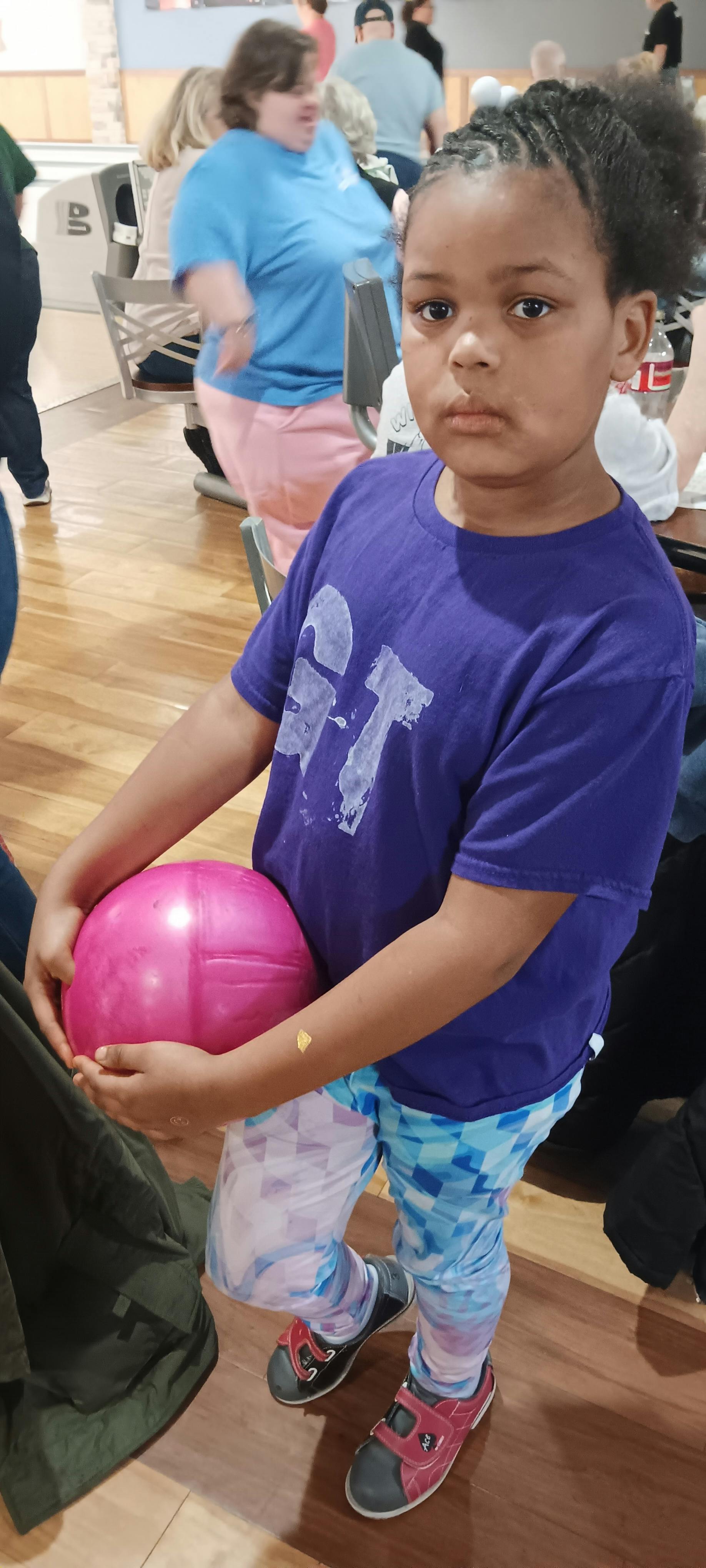 Child holding a pink bowling ball