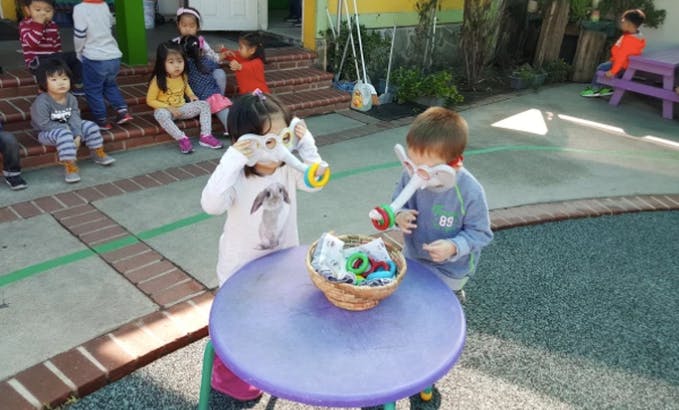 Two children playing with bubble wands at a table outdoors
