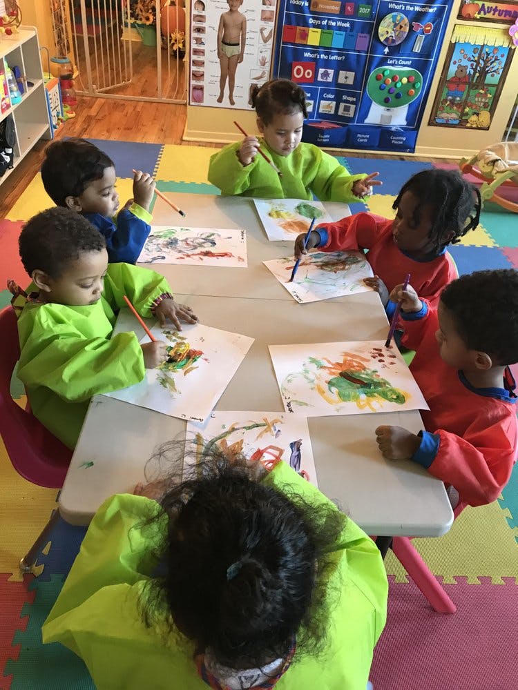 Children painting at a table in a classroom