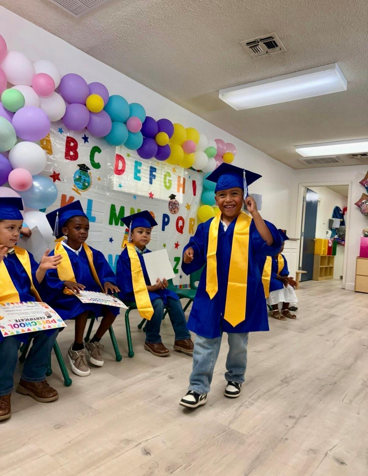 Children in graduation caps and gowns in a classroom