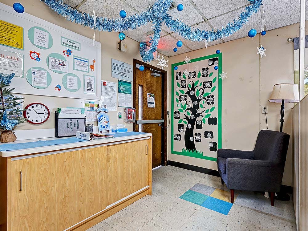 Reception area with a wooden counter, bulletin board, and armchair