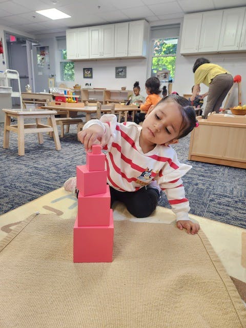 Child stacking pink blocks in a classroom
