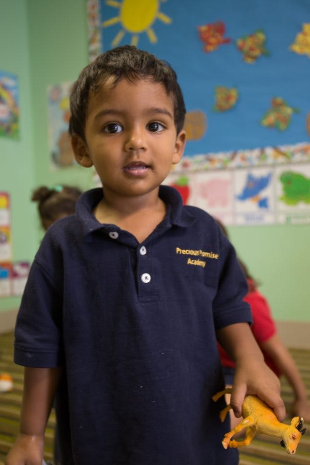 Child in a blue polo shirt holding a toy animal
