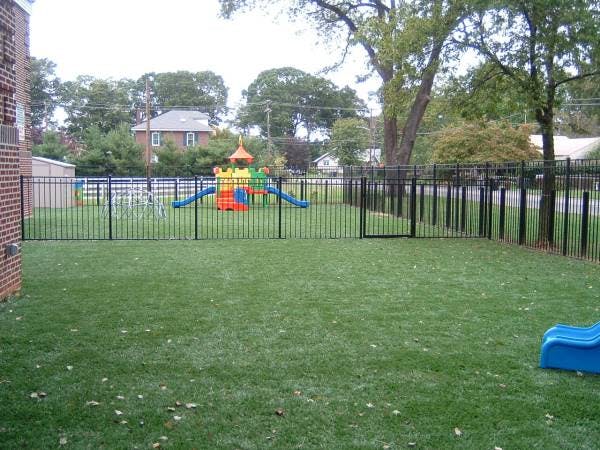 Fenced playground with colorful play structure and green grass