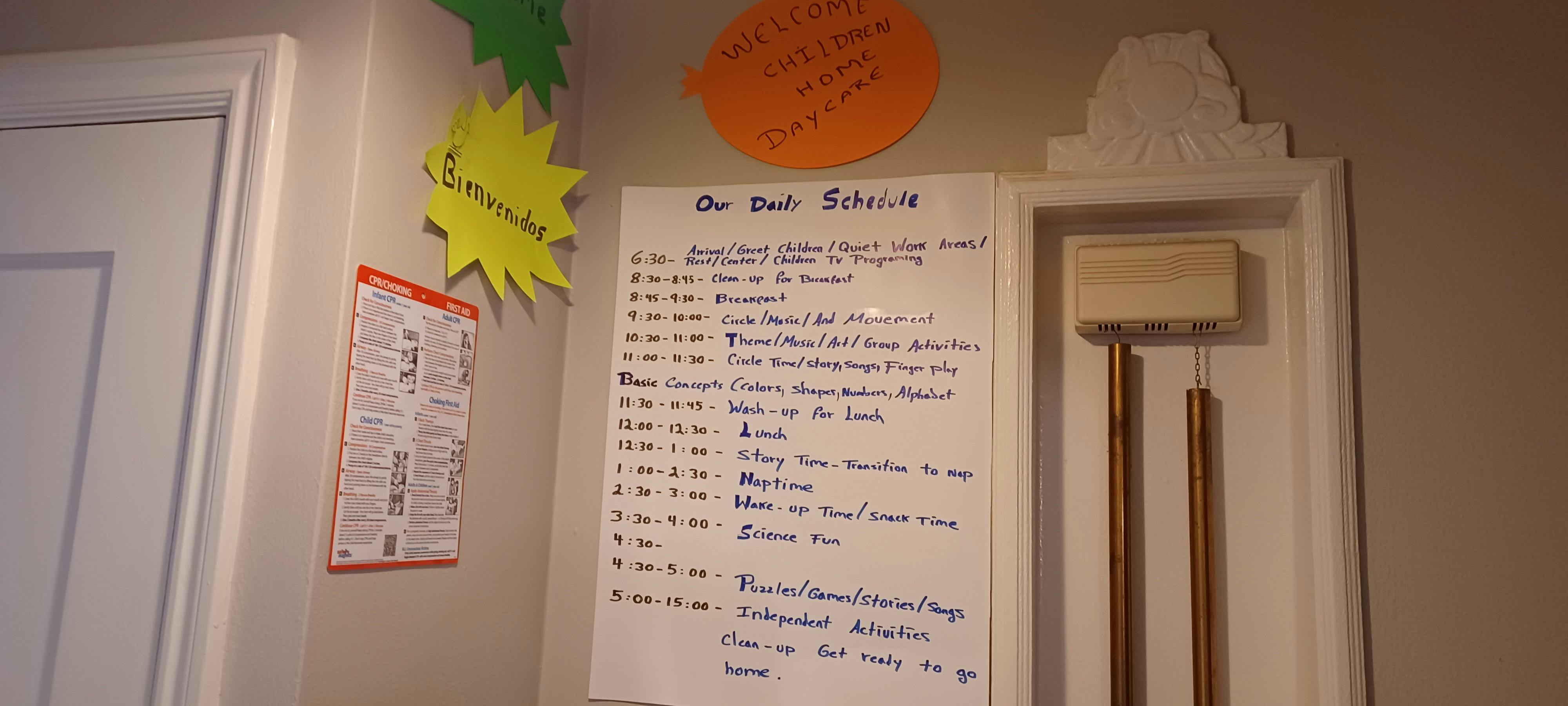 Handwritten daily schedule on a white board with chimes next to it