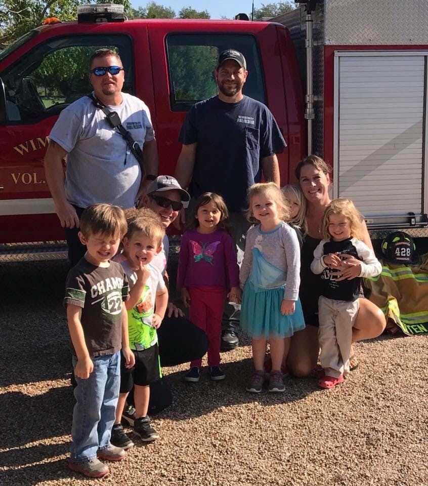 Two people and several children posing in front of a red truck