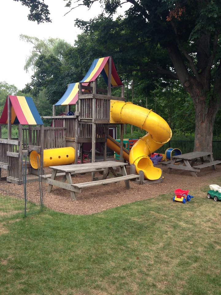 Playground with yellow slides, tunnels, and picnic tables