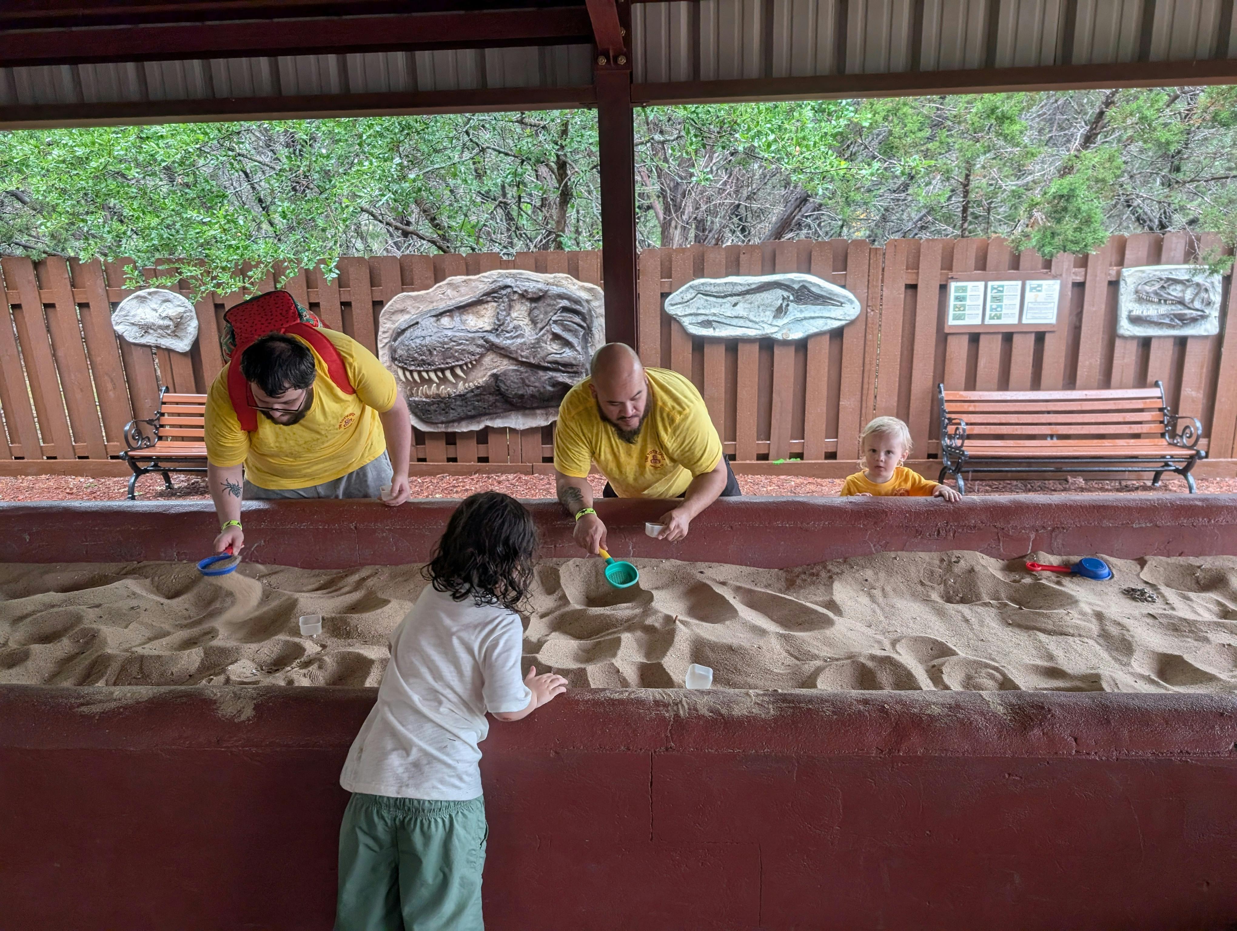 People and children playing in a large sandbox