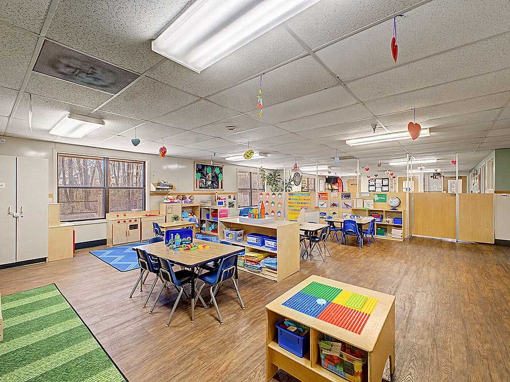 An empty children's classroom with small tables and chairs
