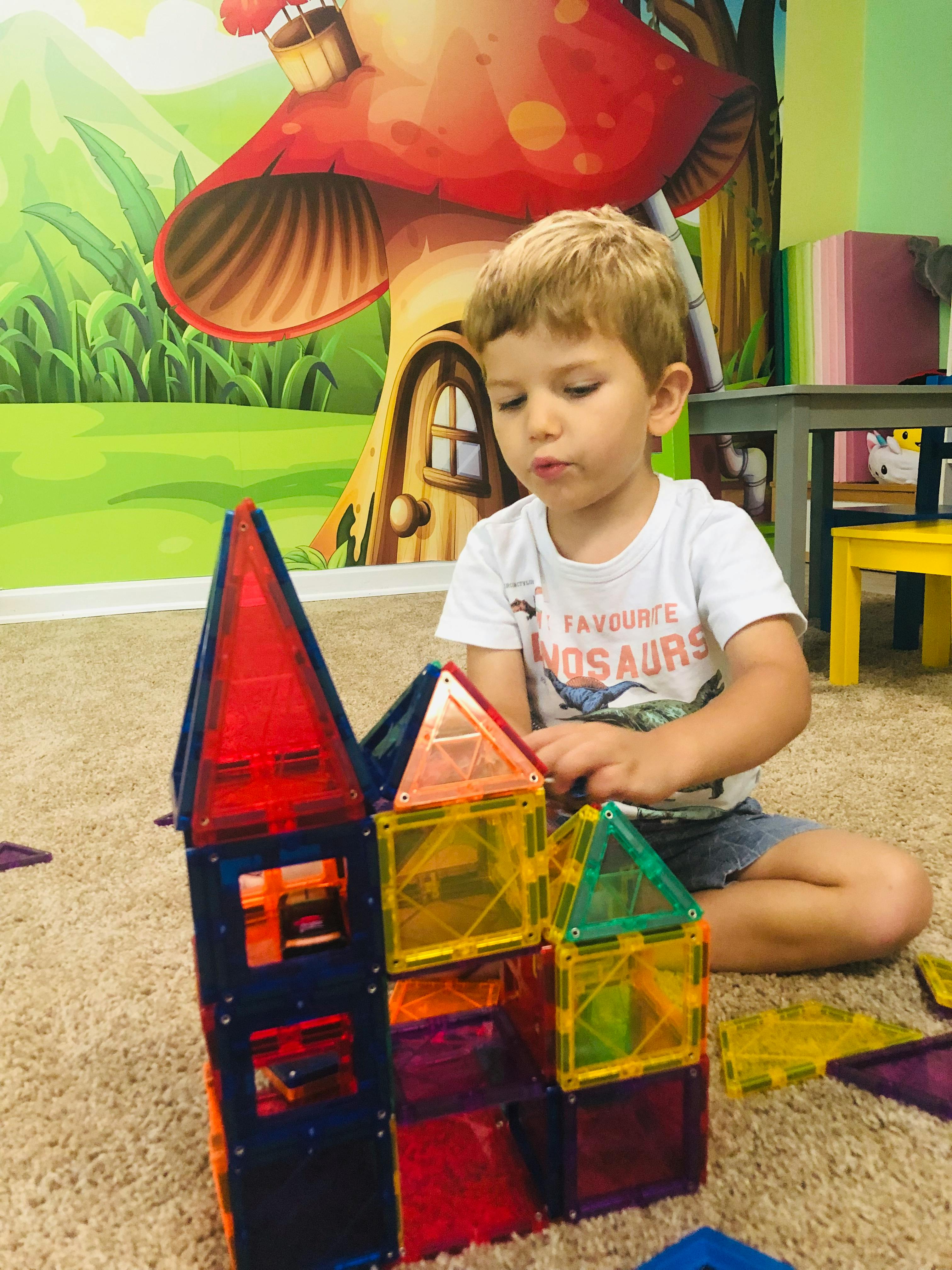 Child playing with colorful magnetic building blocks on the floor