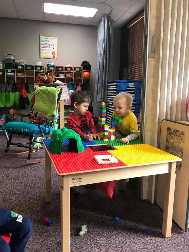 Two children playing with building blocks at a table