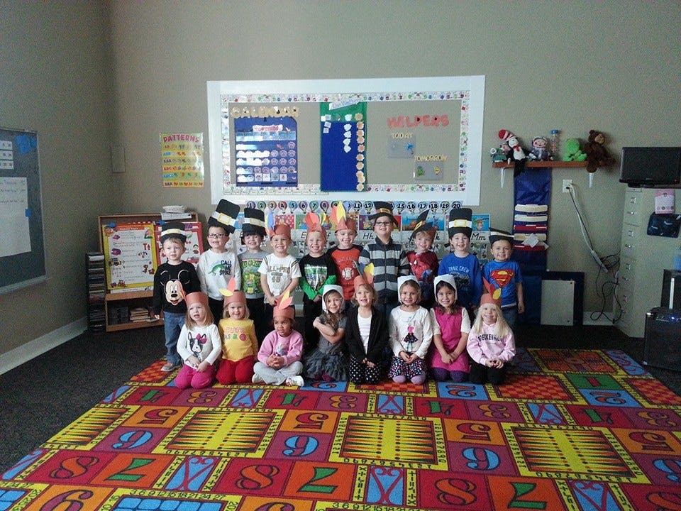 Group of children in costumes standing and sitting in a classroom