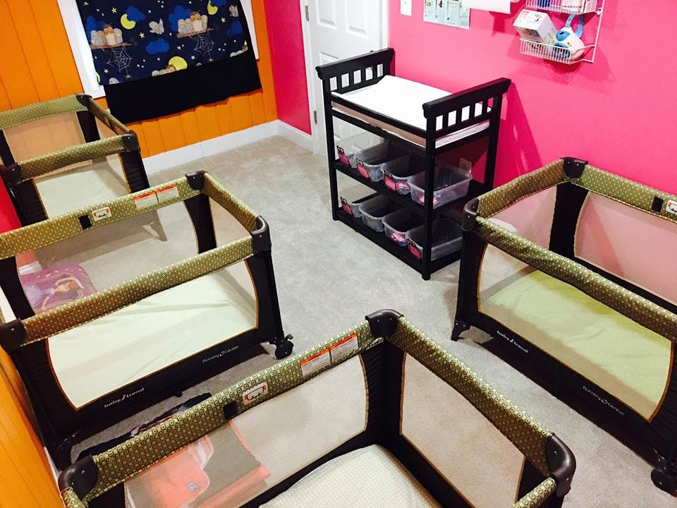 Multiple portable cribs and a changing table in a room