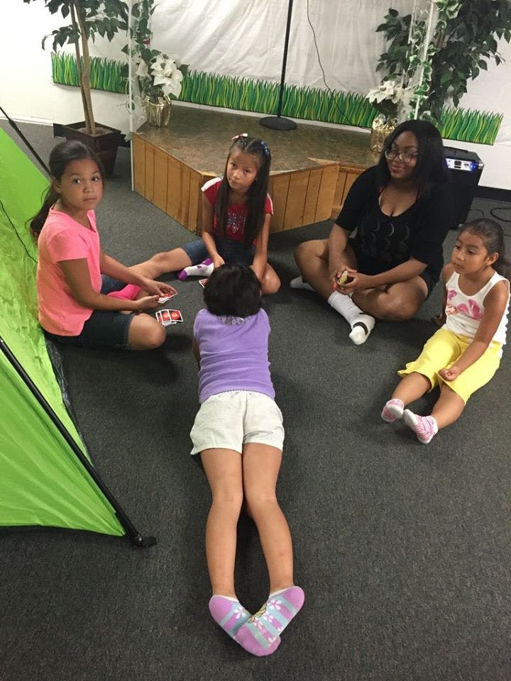 Adult and children sitting on floor playing cards
