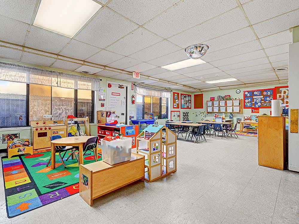 Empty children's classroom with small tables and chairs