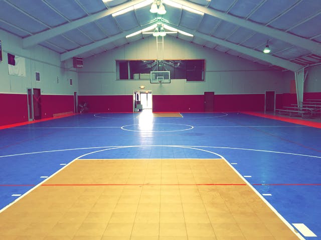 Empty indoor basketball court with blue and tan floor