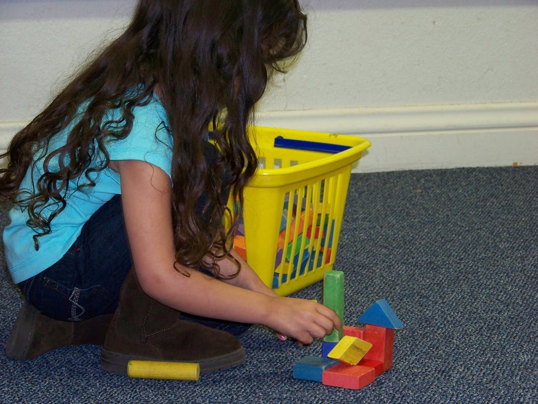 Child playing with colorful building blocks on a carpeted floor