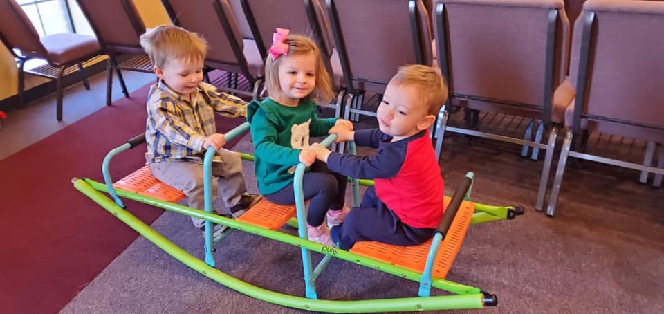 Three children on a seesaw rocker