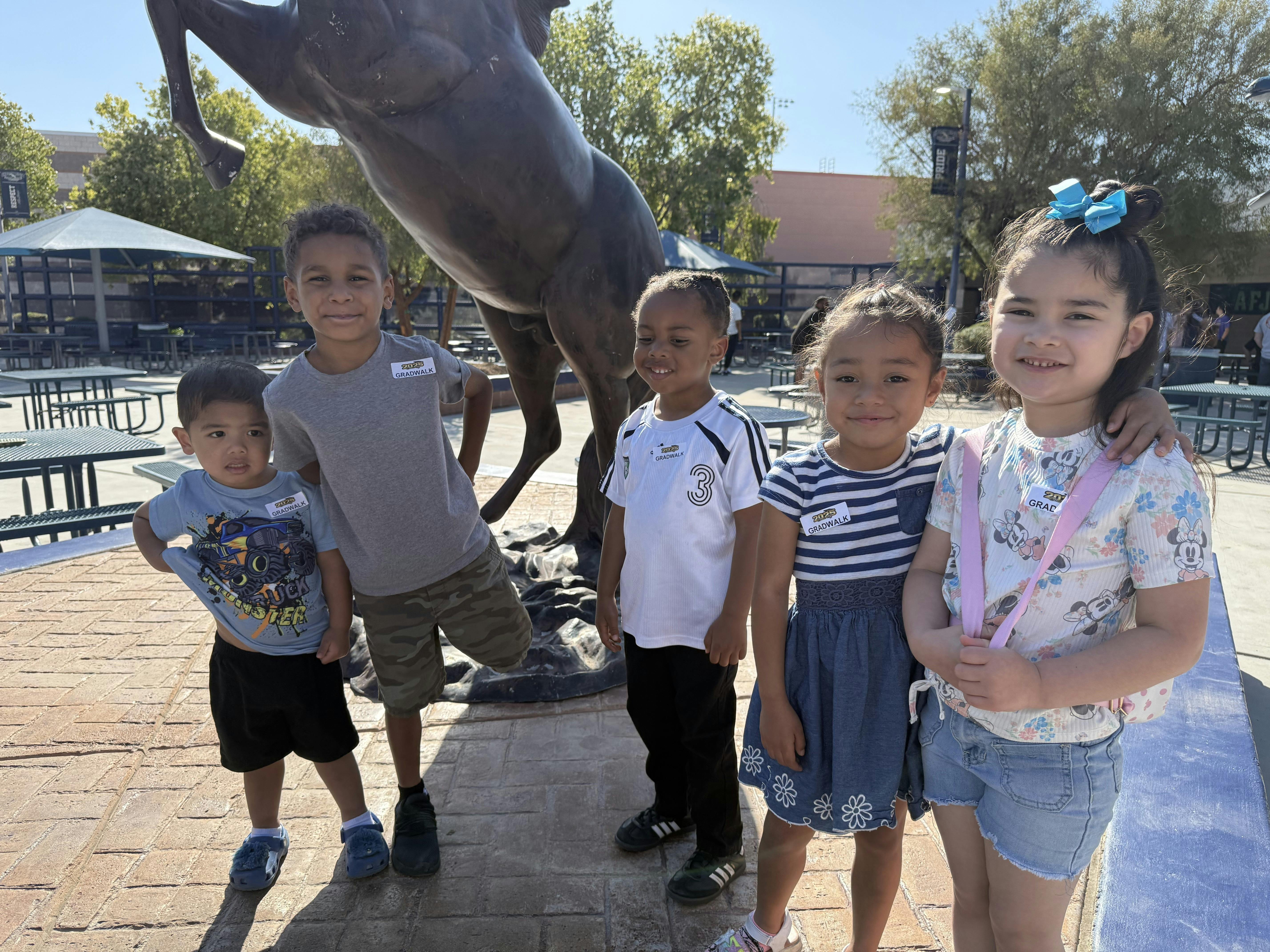 Five children posing outdoors near a statue