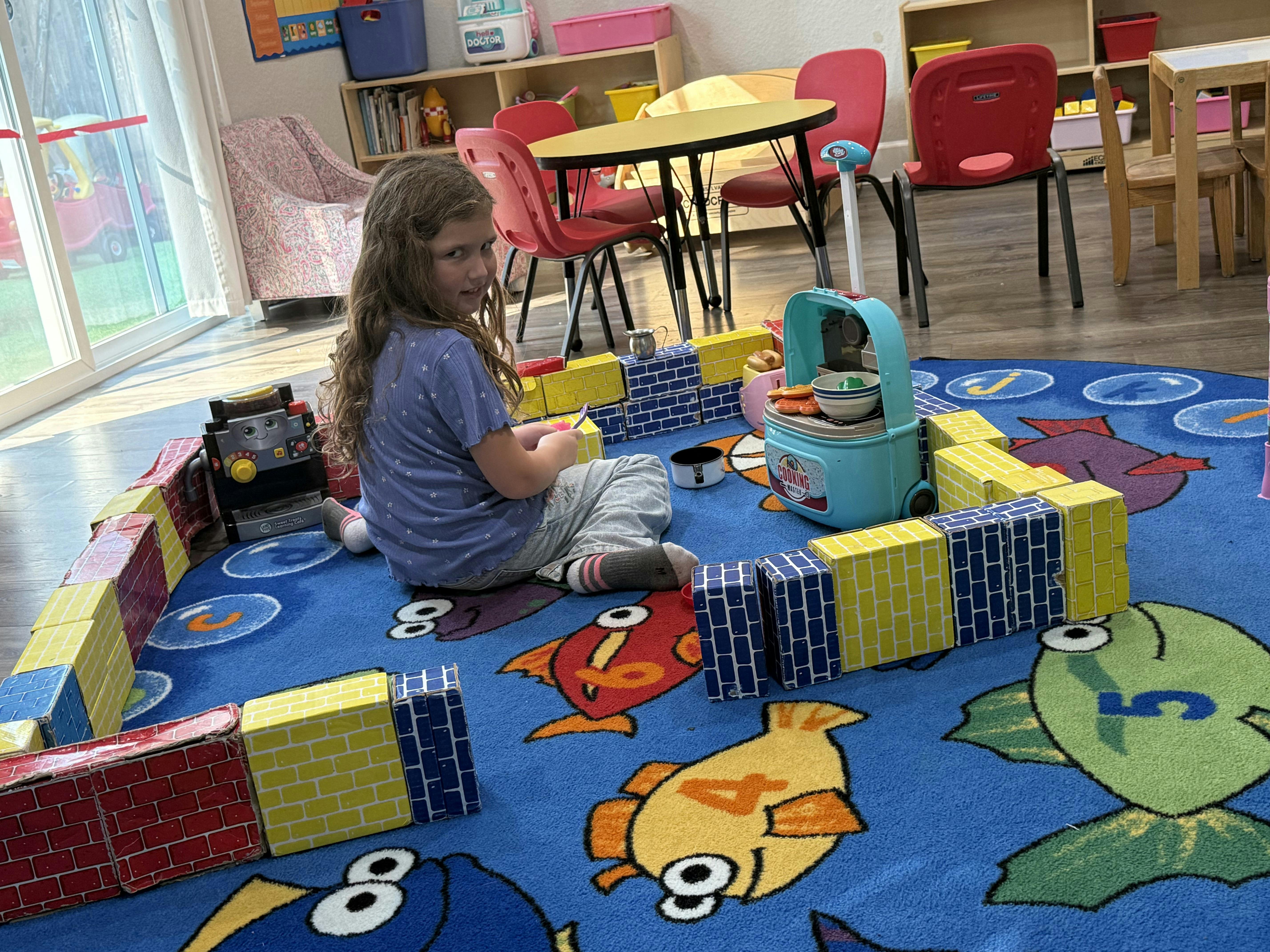 Child playing with blocks and toy kitchen in a classroom