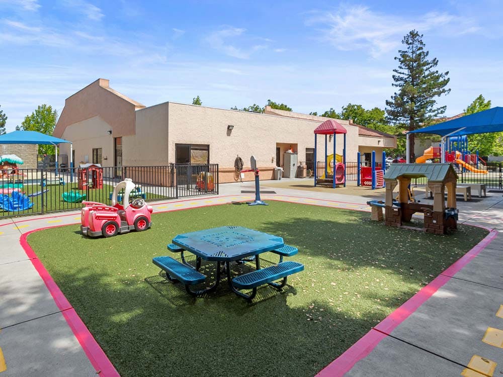 Playground with swings, slides, a small playhouse, and a picnic table