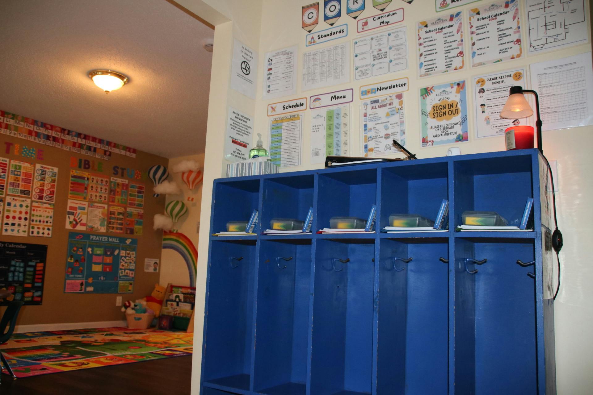 Classroom entryway with blue cubbies and a bulletin board full of colorful signs