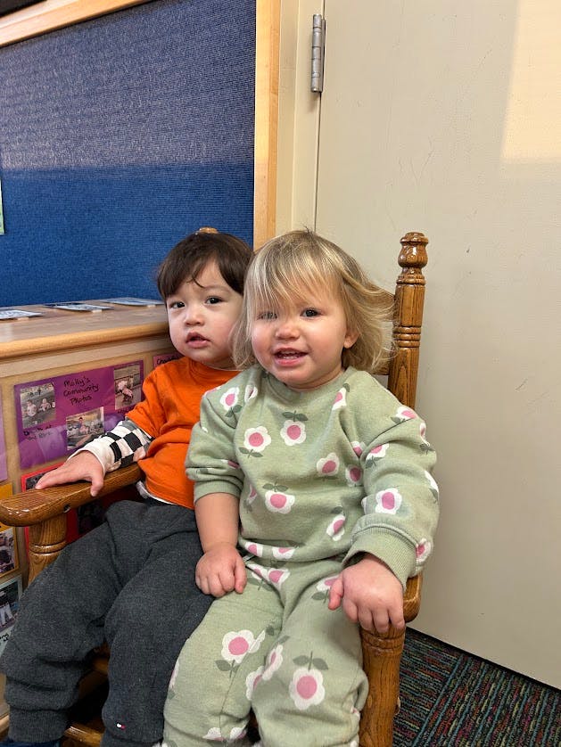 Two children sitting together in a wooden rocking chair