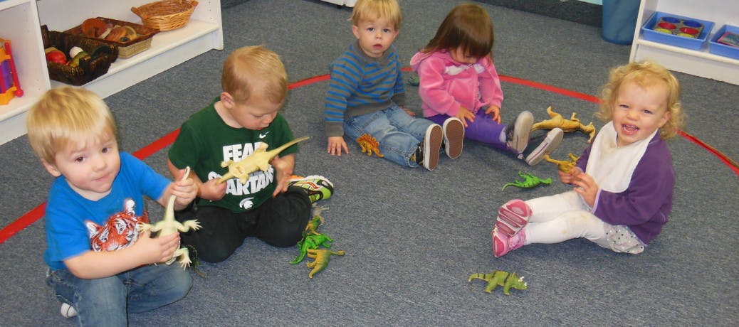 Children playing with toy dinosaurs on the floor