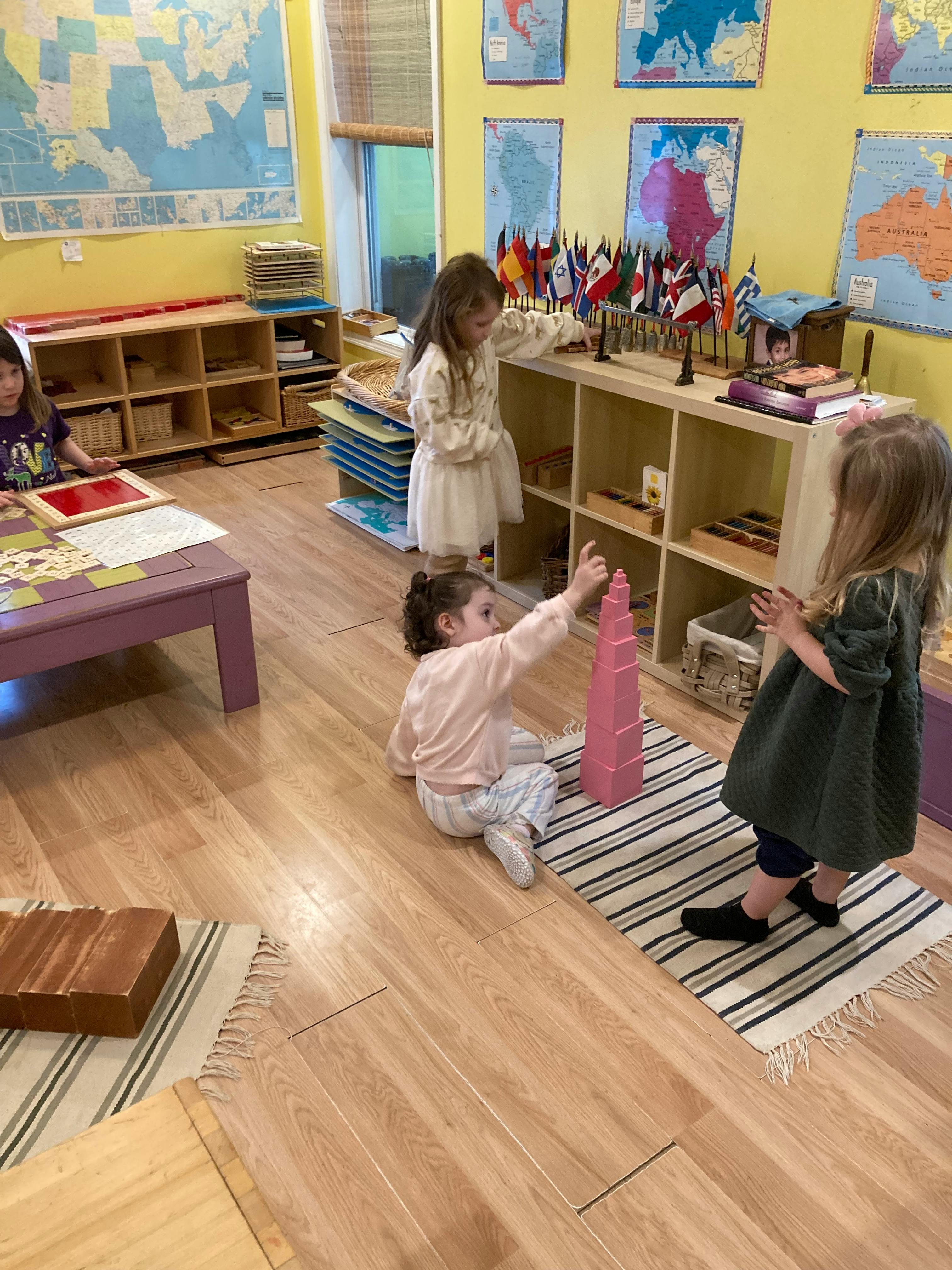 Three children playing with educational materials in a classroom