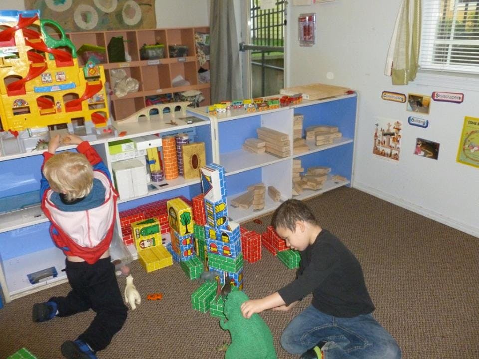 Two children playing with building blocks on the floor in a room