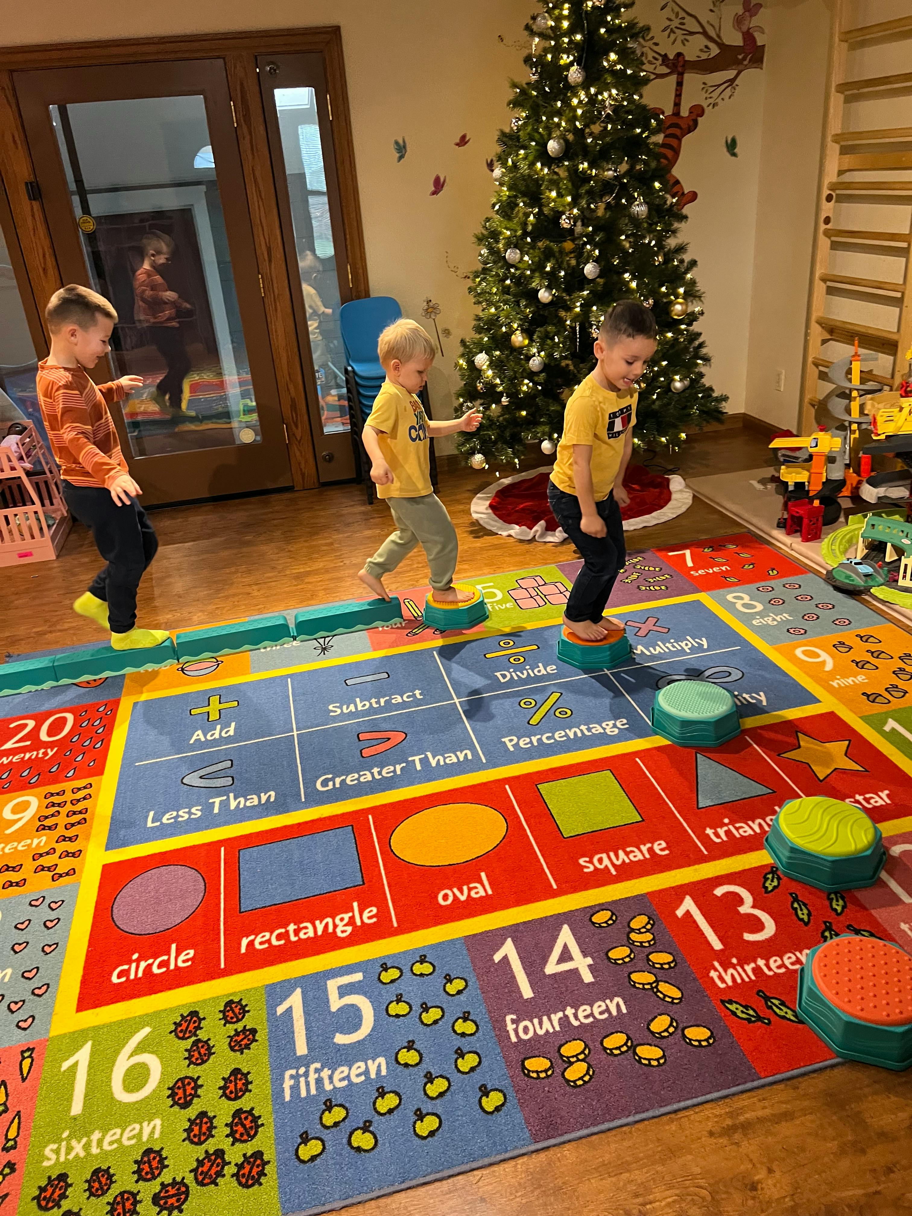 Three children playing on a colorful educational rug