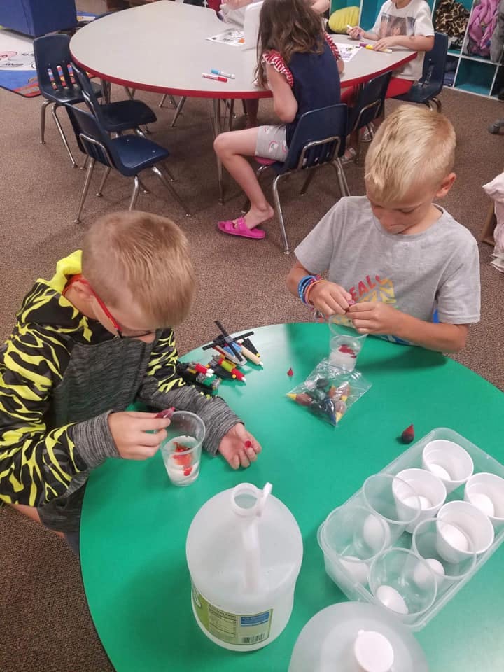 Two children at a table working on a craft project